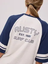 Remera bicolor Rusty con cuerpo verde lima y mangas ranglán grises con dos rayas blancas en los puños. Estampado frontal con el logo de la marca y el número 85.