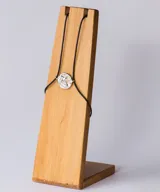 Pulsera con cordón negro y dije redondo plateado con diseño de estrella de mar.