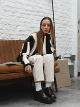 Sweater de tejido de punto con rayas horizontales en blanco y negro, con ribete marrón en los bordes.