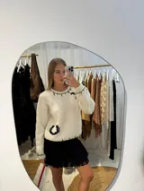 Buzo de lana merino tejido a mano en color crudo, con diseño de herradura y pespuntes decorativos en color negro. Presenta cuello redondo, mangas largas y un calce relajado.