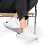 Zapatillas urbanas blancas con detalles plateados en el talón y la suela. Cierre con cordones blancos.