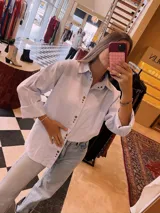 Camisa celeste y blanca a rayas verticales, con botones metálicos a presión, corte relajado y cuello clásico.