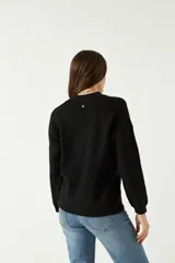 Sweater negro de punto suave con cuello redondo y hombros caídos.