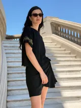 Remera negra de corte holgado con mangas cortas con volados y detalle de apliques de piedras en los volados.