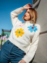 Sweater tejido color rosa con cuello redondo y bordados de flores de colores.