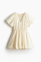 Vestido corto color crema con escote en V pronunciado, mangas globo cortas con diseño raglán, costura elástica en la cintura y pollera globo con volumen.