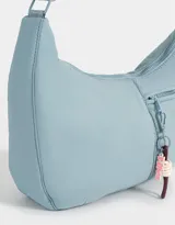 Cartera saca negra de tela deportiva con correa regulable, cierre superior y bolsillo frontal con cierre. Incluye charm lateral.