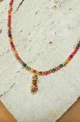 Collar corto de cuentas facetadas de colores rojo, naranja, verde y dorado, con dije de mano de Fátima dorada con detalles de strass.