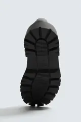 Mocasín negro con flecos. Parte superior lisa con efecto desgastado. Detalle de antifaz y flecos con puntas metálicas en el empeine. Horma cuadrada. Suela con volumen.