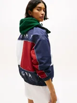 Campera náutica amplia reversible de nailon, con diseño color block en rojo, blanco y azul marino. Tiene capucha fija, cierre de cremallera oculto con botones a presión, puños y bajo elásticos, dos bolsillos ribeteados en la cintura, parche con logo de Tommy Hilfiger en el pecho y logo de Tommy Hilfiger en el cuello, las mangas y la espalda.