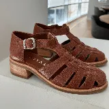 Sandalias franciscanas de cuero color marrón con tiras entretejidas, hebilla lateral y taco bajo de madera.