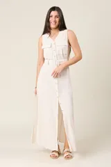 Vestido camisero largo sin mangas color negro, con cuello en V y cierre de botones delanteros. Incluye cinturón ancho a tono y bolsillos estilo safari en el pecho.