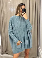 Sweater tejido de punto color fucsia con diseño de trenzas verticales en color naranja. Tiene cuello redondo y dos bolsillos frontales.