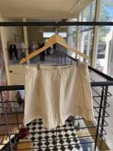 Conjunto beige de lino rayado, compuesto por un chaleco corto con botones y una minifalda cruzada con volantes.