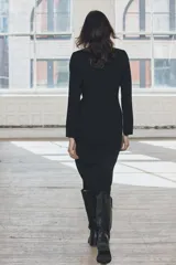 Vestido midi negro de escote pico y manga larga con hombreras. Tiene falsos bolsillos de vivo en el delantero y cierre en la espalda con cremallera oculta.