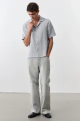 Camisa de manga corta color gris claro, de punto con textura de mezcla de algodón. Modelo con cuello abierto, tapeta lisa y bajo recto. Corte estándar para una silueta clásica y cómoda.