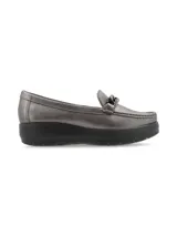 Mocasín de cuero charol negro con plataforma blanca y detalle de hebilla metálica plateada en el empeine.