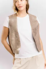 Chaleco de cuero color marrón con estampado brillante, de corte recto y largo a la cintura. Su diseño abierto en el frente lo convierte en una prenda versátil, fácil de combinar tanto con básicos como con looks más elaborados.