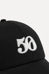 Gorra negra de algodón con visera y bordado frontal con el número 50 en blanco.