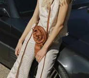 Bolso bandolera de cuero color camel con forma de rosa.