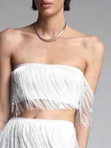 Conjunto de top y falda con flecos, color blanco y diseño elegante.