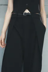 Pantalón negro de tiro medio con cinturón a tono con hebilla metálica, bolsillos delanteros y falsos bolsillos traseros.
