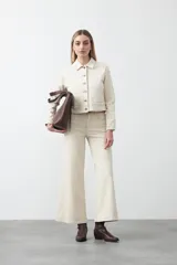 Pantalón de denim azul oscuro con corte flare, ajustado en la cadera y amplio en el ruedo. Presenta pespuntes a contratono en color blanco que resaltan las costuras.