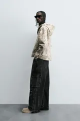 Pantalón relaxed fit de denim negro con efecto lavado, bolsillos frontales, traseros de plastrón y multifunción en perneras. Bajo ajustable con trabilla y cierre frontal con cremallera y botón.
