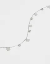 Collar corto dorado con cadena de eslabones pequeños, dijes de trébol de cuatro hojas y dijes redondos con cristales engarzados.