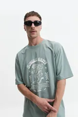 Remera color rosa claro de corte oversize y mangas cortas. Estampado frontal con la leyenda "Jungle Army", un tigre y otros símbolos.