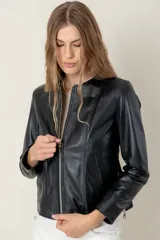 Campera de cuero ovino negro, estilo clásica, con cuello a la base, cierre frontal metálico y bolsillos laterales con cierre.