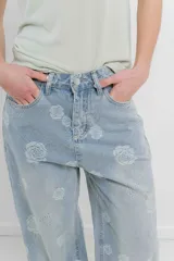 Pantalón de jean celeste de tiro alto y corte ancho, con bordado de flores grandes en hilo blanco hueso.