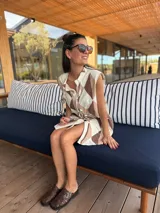 Vestido camisero corto con estampado de rombos en tonos beige, marrón y blanco. Tiene cuello camisero, cierre frontal con botones y corte holgado.