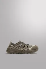 Zapatilla deportiva color beige con aberturas laterales, ajuste de cordones y suela de goma.