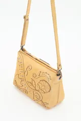 Cartera bandolera de cuero vacuno color verde bosque, con diseño floral bordado y tachas metálicas en tonos dorados y plateados envejecidos. Posee correa regulable y cierre superior.