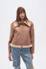 Campera negra de estilo aviador, confeccionada en material tipo gamuza o suede, con cuello y forro de corderito (shearling) negro. Presenta cierre frontal metálico y puños y ruedo con terminación de corderito.