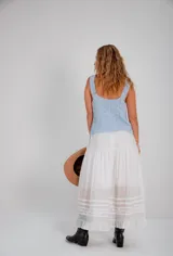 Falda larga blanca de estilo romántico, con volados en el ruedo y detalles de puntilla y encaje bordado.