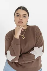 Buzo marrón de corte holgado con cuello redondo y mangas largas con estampado de estrellas en los codos.