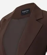 Blazer sastre color marrón, de corte alargado y ligeramente entallado. Presenta cuello solapa clásico, cierre frontal con un solo botón y forro interno. Las mangas son largas y en la espalda tiene un recorte central con tiras ajustables entrelazadas para un lazo personalizado.