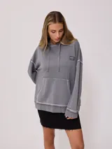 Canguro gris con capucha corta, bolsillo tipo canguro y parche con logo de la marca Rusty en el pecho. Tiene efecto lavado y costuras a la vista.