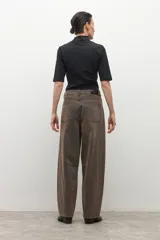 Pantalón de jean estilo barrel, color marrón oscuro con efecto desgastado. Presenta un calce holgado y tiro alto.