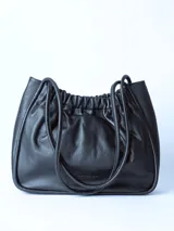 Bolso totebag negro de cuero con fruncido superior y doble asa fina.