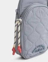 Portacelular gris acolchado de tela deportiva con bolsillo frontal con cierre y puller de goma. Tiene correa regulable y desmontable y cierre superior.