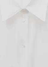 Camisa blanca de algodón con cuello camisero, corte recto, mangas largas con pliegues y puños abotonados.