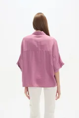 Camisa holgada de viscosa color rosado, con cuello camisero, manga corta y cierre frontal de botones.