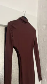 Top marrón de mangas largas con cuello alto y abertura en la cintura.