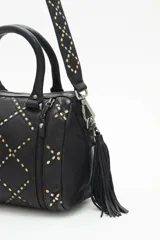Cartera negra de cuero vacuno con correa desmontable, doble asa corta y cierre superior. Diseño matelassé con tachas metálicas plateadas y doradas en el frente y laterales con cierre.