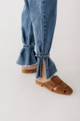 Pantalón de jean azul oscuro de corte recto, con cintura alta con cinturón del mismo material y detalle de flecos en la cintura y en los tobillos.