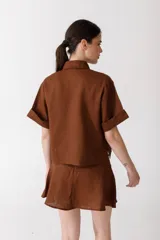 Camisa corta de manga corta color rojo, con doble cartera diagonal con botones de madera, cuello clásico y botamangas marcados. Tiene un bolsillo con aplique de crochet hecho a mano con forma de frutilla.