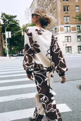 Pantalón de tiro alto con delantero cruzado y broche, con estampado floral en tonos marrones sobre fondo crudo.